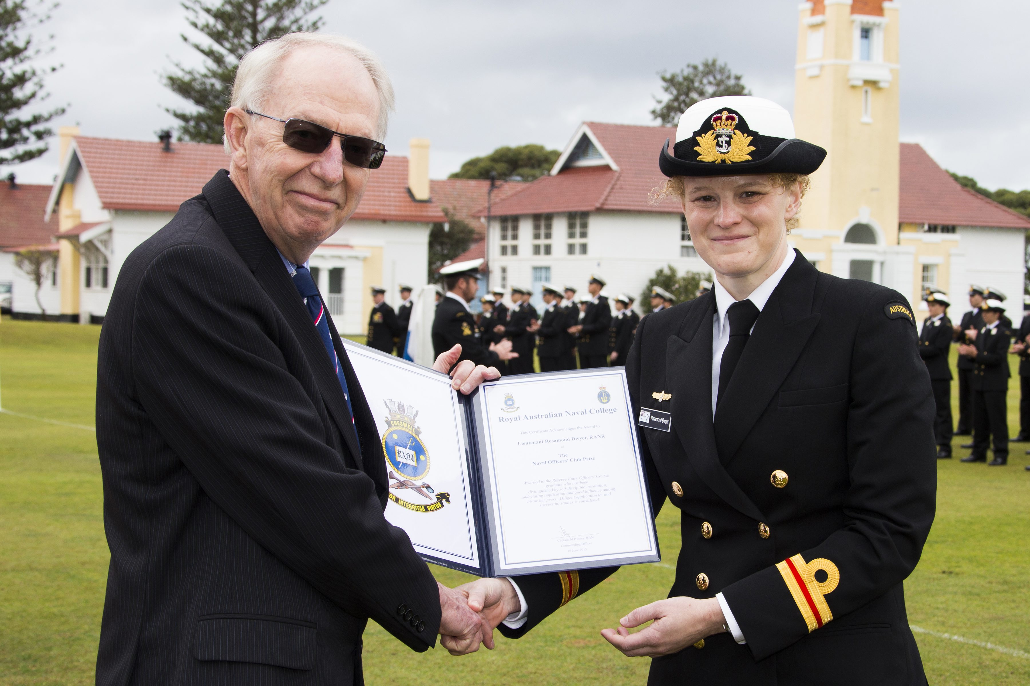 (L-R) Captain R. Bayley, RAN, (Retd) presents Lieutenant Rosamond Dwyer with the Naval Officers' Club Prize, for being the Reserve Entry Officers' Course member who displayed the best course results as well as self-discipline, resolution, undeviating application and good influence among her peers. *** Local Caption *** Graduates from New Entry Officer Course (NEOC) 52 celebrated the end of 20 weeks of intensive training at their Passing Out Parade at HMAS Creswell. The new officers paraded as a guard on HMAS Creswell Quarterdeck and marched past the Reviewing Officer, Governor-General, His Excellency General the Honourable Sir Peter Cosgrove AK MC (Retd) At NEOC 52 graduation, the Royal Australian Navy observed 100 years of training excellence at HMAS Creswell. The first Cadet Midshipmen to undertake Officer initial entry training arrived at the base in 1915.